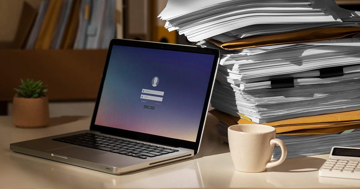 laptop with a pile of papers